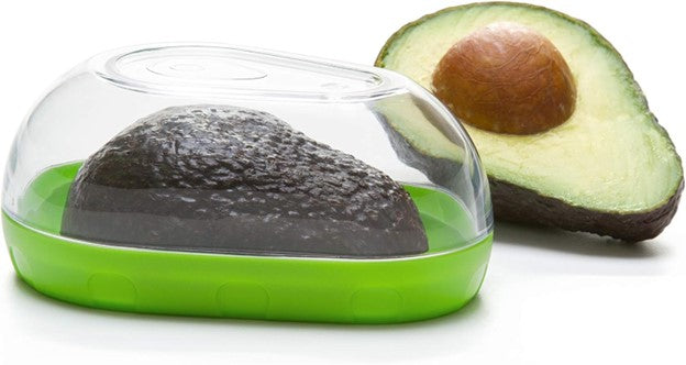 airtight avocado storage container with avocado half inside and an avocado half with pit adjacent to container