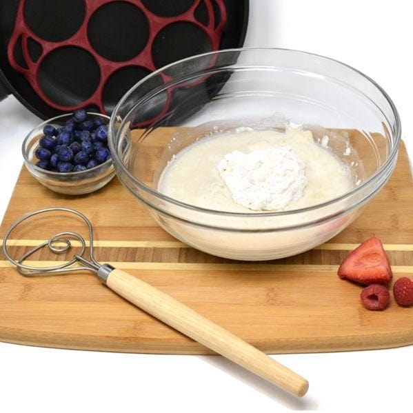 Norpro 12'' Danish Dough Whisk sitting on top of bread board with glass cup of blueberries next to mixing bowl with sourdough muffin batter and strawberries and raspberries on top of board