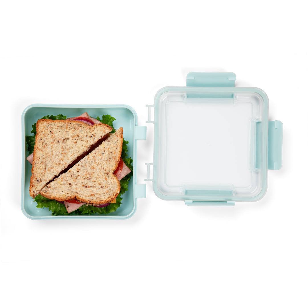 top view of light blue plastic food storage container with sandwich inside and lid sitting next to storage compartment