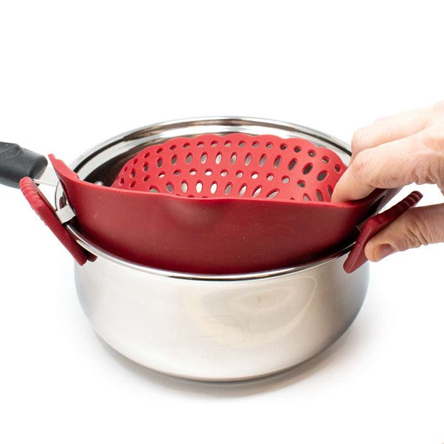 red silicone kitchen strainer being clipped onto silver stainless pot